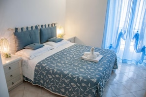 A neatly made bed with a floral bedspread, two pillows, and a folded towel on the foot of the bed. - Bed and Breakfast Loggetta (Tarquinia)