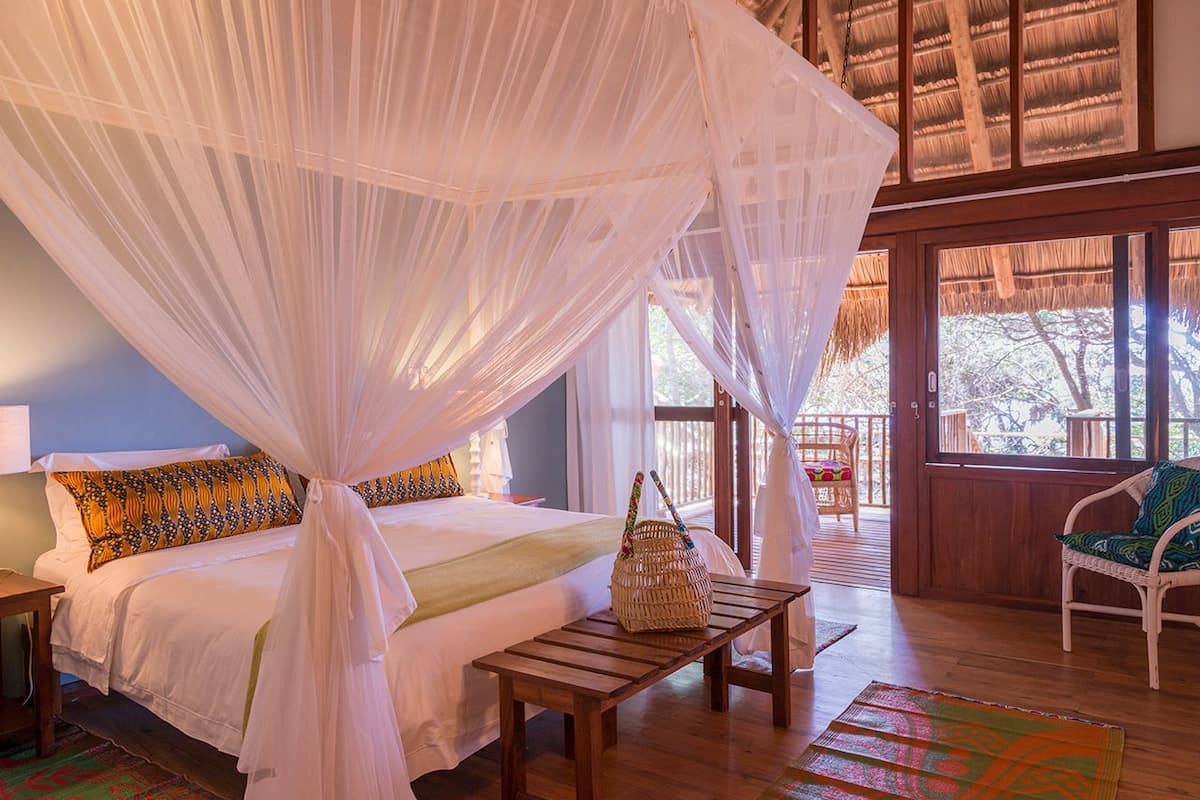 A room with a bed under a canopy, a wooden table, and a wicker basket.