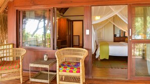 A room with a bed, a wicker chair, and a small table. - Cabo Beach Villas (Machangulo)