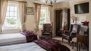 A hotel room with two beds, a wooden wardrobe, a desk, a chair, and a TV mounted on the wall. - Hardwick Farm (Abergavenny)