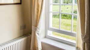 A room with a large window, white curtains, and a framed picture on the wall. - Hardwick Farm (Abergavenny)