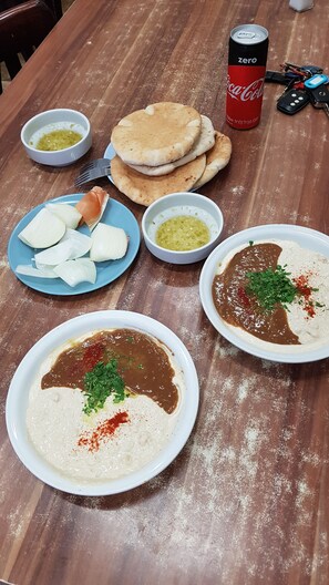 Una mesa con platos de hummus, pan de pita y una lata de Coca-Cola.