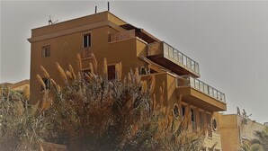 A multi-story building with balconies and windows, surrounded by vegetation. - Sea Front Penthouse (Tel Aviv)