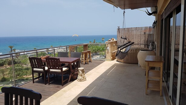A wooden deck with a table and chairs overlooking the ocean. - Sea Front Penthouse (Tel Aviv)