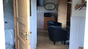 A wooden door leading to a bathroom with a toilet and sink. A dining area with a table and chairs is visible in the background. - Finspångs Golfklubbs Stugby (Finspang)