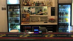 A bar with a clock, shelves of liquor, and a cash register. - Finspångs Golfklubbs Stugby (Finspang)