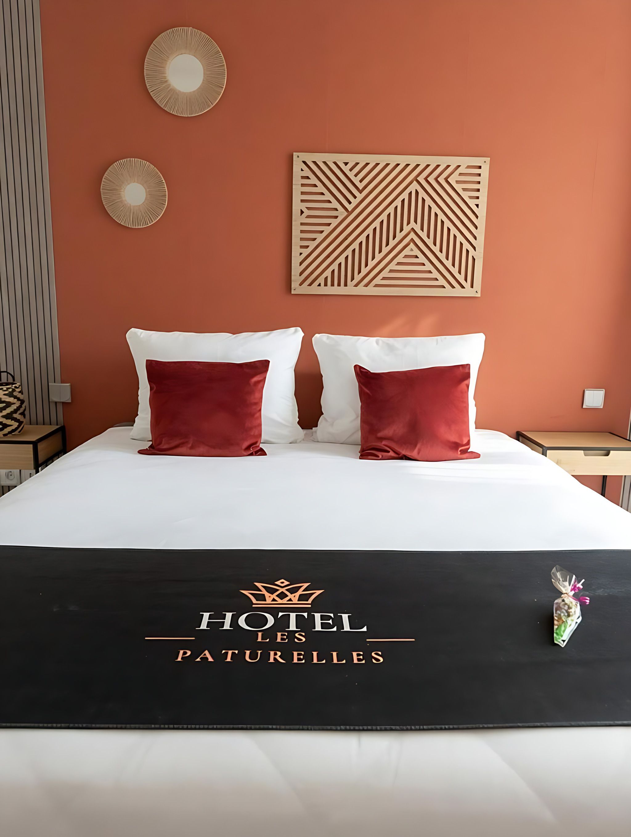 Une chambre d’hôtel avec un lit, deux oreillers, un élément décoratif mural et un panneau posé sur le lit.