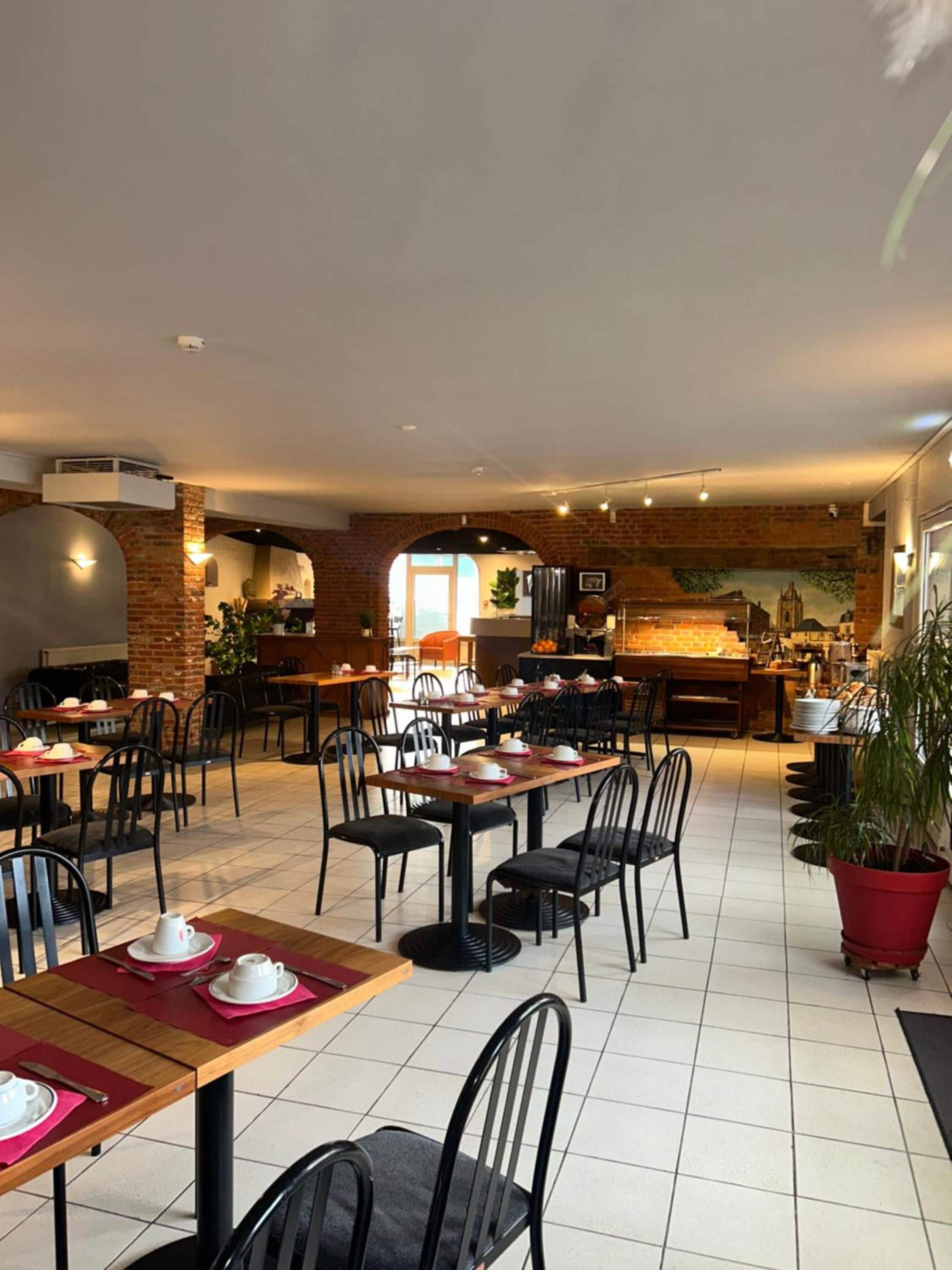 A restaurant with multiple tables and chairs, a brick wall, and a view of the cityscape.