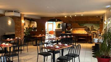A restaurant with multiple tables and chairs, a brick wall, and a view of the cityscape.