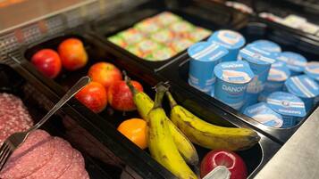 Un bufé con diferentes opciones de comida, incluyendo carnes frías, frutas y productos lácteos.