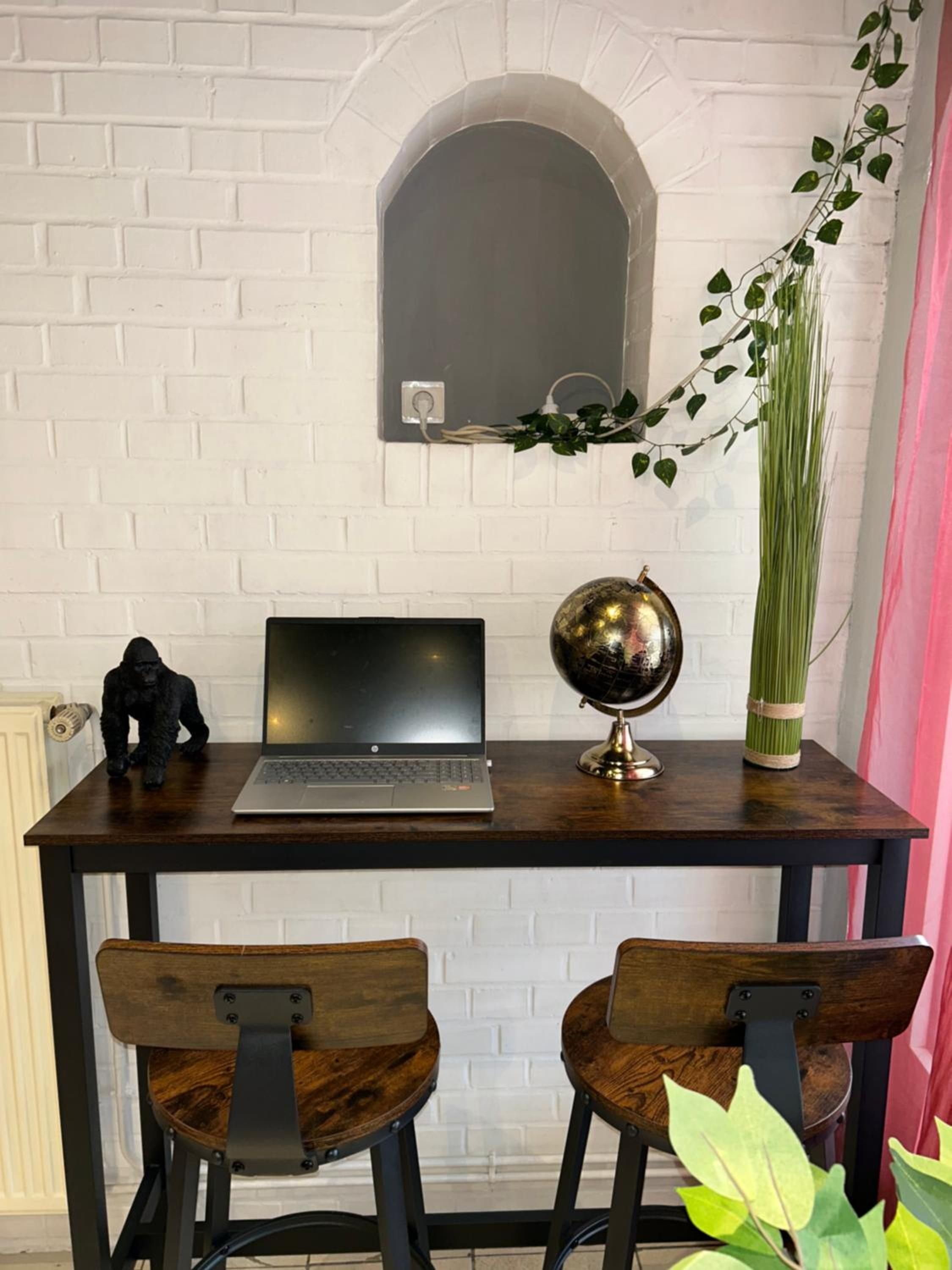 Un espacio de trabajo con una computadora portátil, un globo terráqueo y una planta sobre una mesa de madera.
