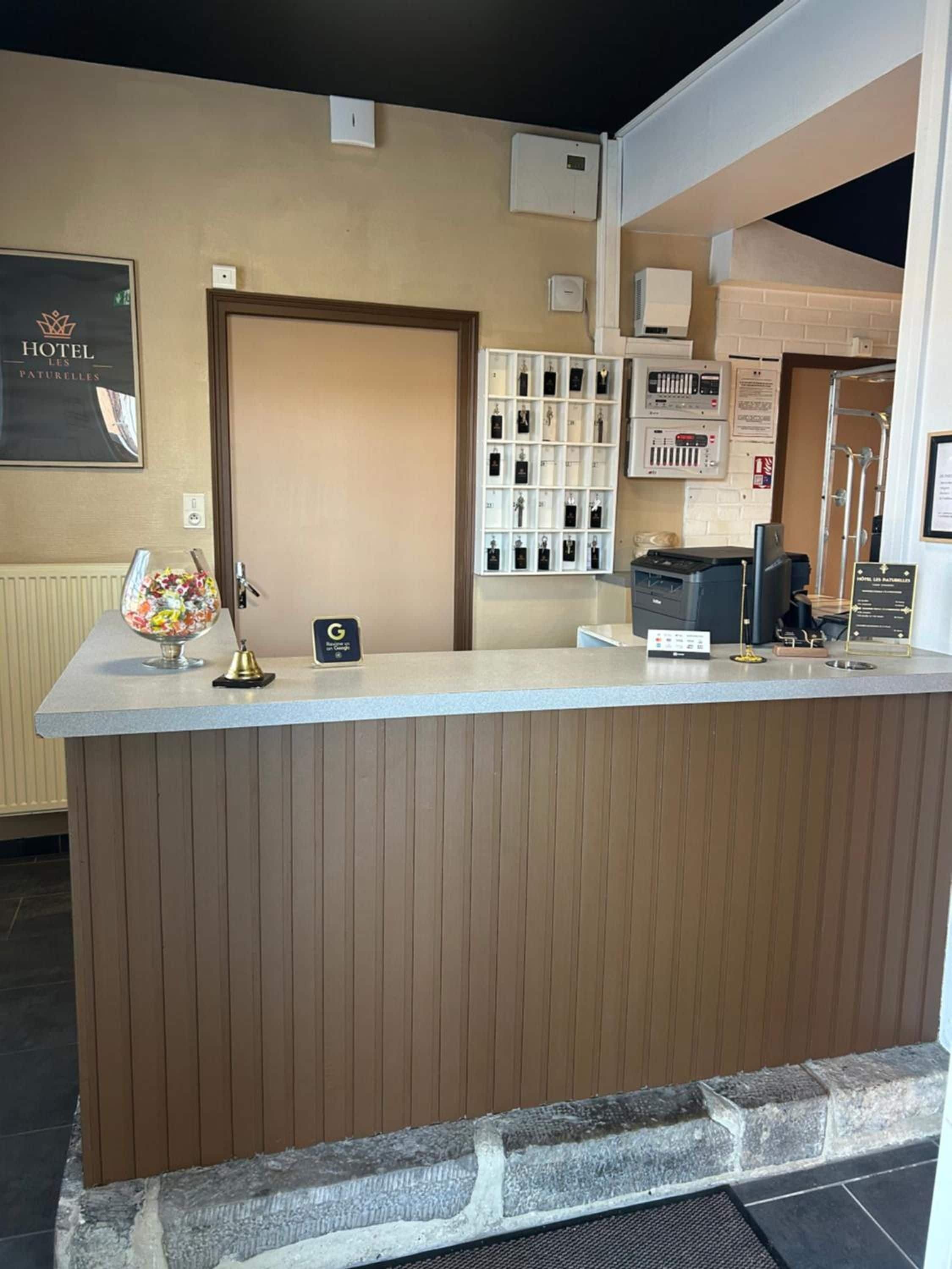 A hotel reception area with a wooden reception desk, a framed sign above it, and a wall-mounted display of toiletries.