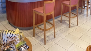 A bar area with a counter, stools, and a display of bottles. - Hôtel Les Paturelles  (Avesnelles)