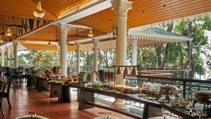 A spacious dining area with a long counter, multiple serving stations, and a view of trees through large windows.