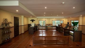 A spacious lobby with wooden benches, a reception desk, and a wall-mounted display.