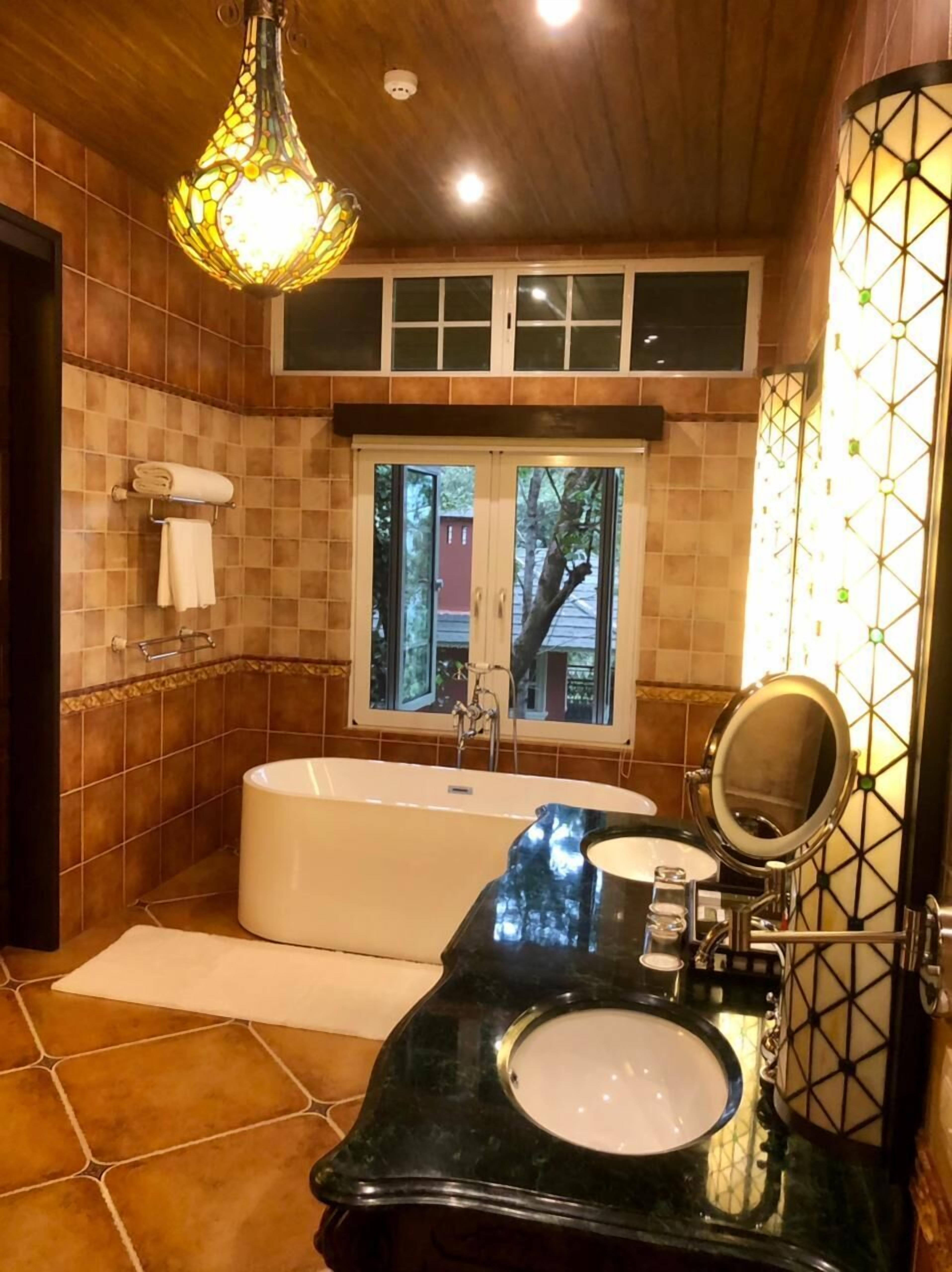 A bathroom with a bathtub, a vanity with a mirror, and a window with a view of the outside.