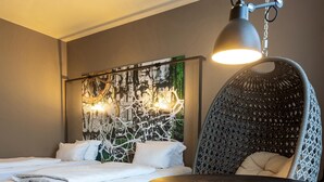 Un dormitorio moderno con una cama grande, una silla colgante y una mesa con silla.