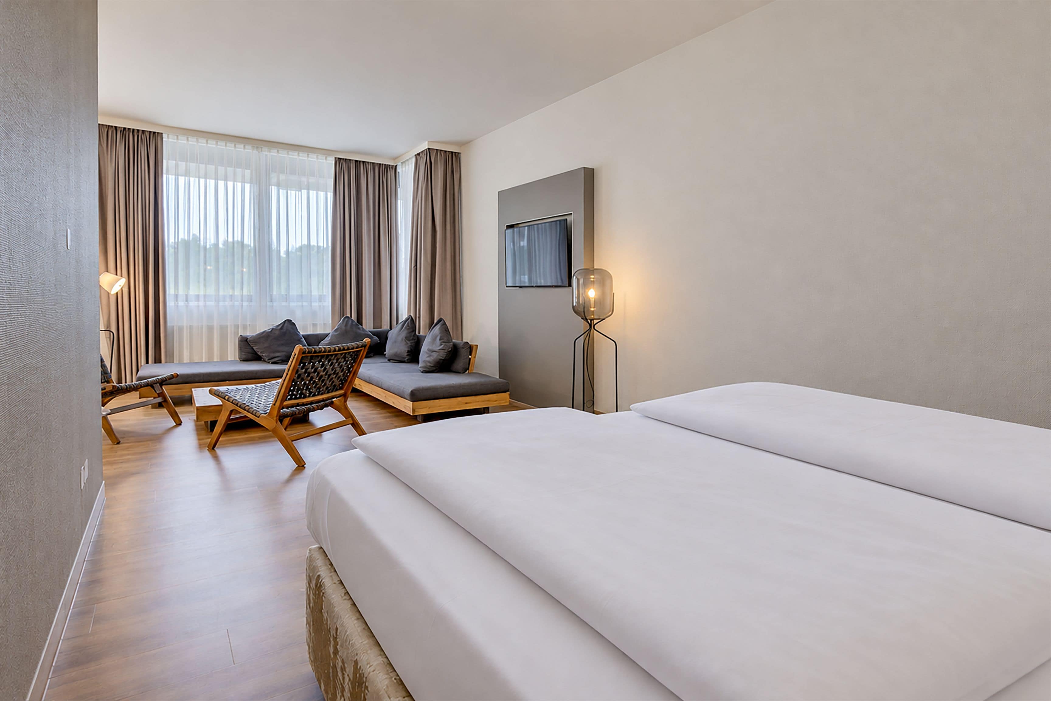 Ein Hotelzimmer mit einem Bett, einer Couch, einem Sessel, einem Schreibtisch und einem Fernseher.