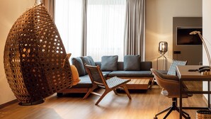 Una sala de estar moderna con un sillón colgante, un sofá y un escritorio con una lámpara.