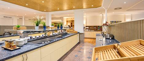 Una cocina moderna de hotel con barra libre, asientos de madera y piso de baldosas.