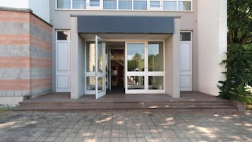 Ein modernes Gebäude mit Glastür, Ziegelverkleidung und einem gepflasterten Eingangsbereich.