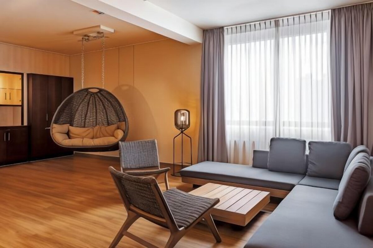 A modern living room with a hanging chair, sofa, and a coffee table.