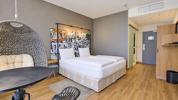 Ein gemütliches Schlafzimmer mit Bett, Pendelleuchte, kleinem Tisch und Stuhl.