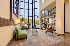 Un hall d’entrée moderne doté d’une grande baie vitrée, de sièges confortables, d’une table basse et d’une bibliothèque.