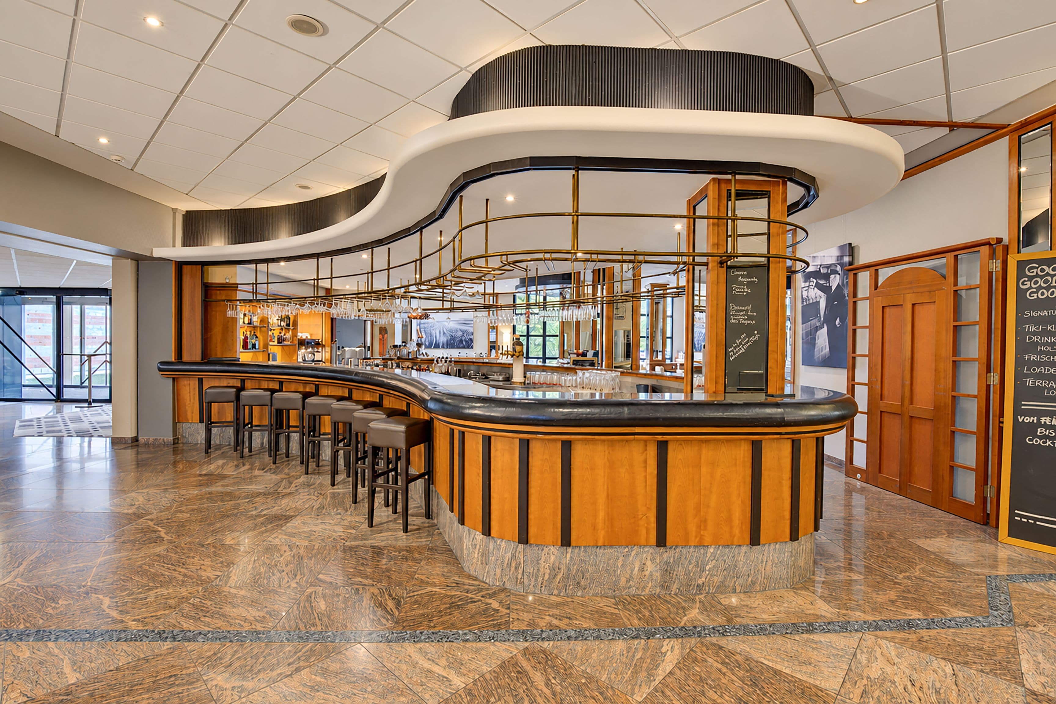 Eine moderne Bar mit einer gebogenen Theke, Barhocker und einer Speisekarte.