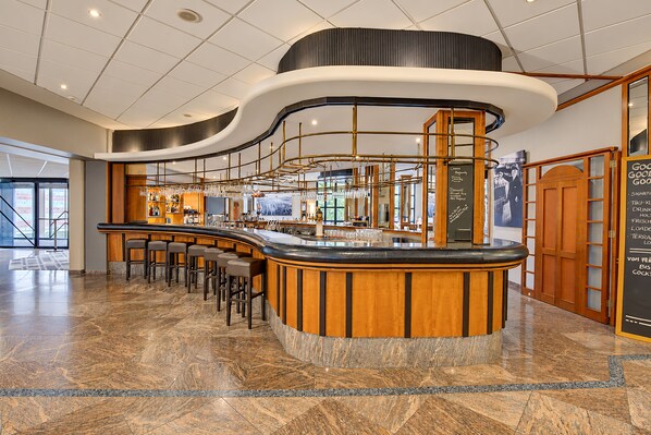 A modern bar area with a curved counter, bar stools, and a menu board. - Seminaris Sunday Hotel Nürnberg (Nuremberg)