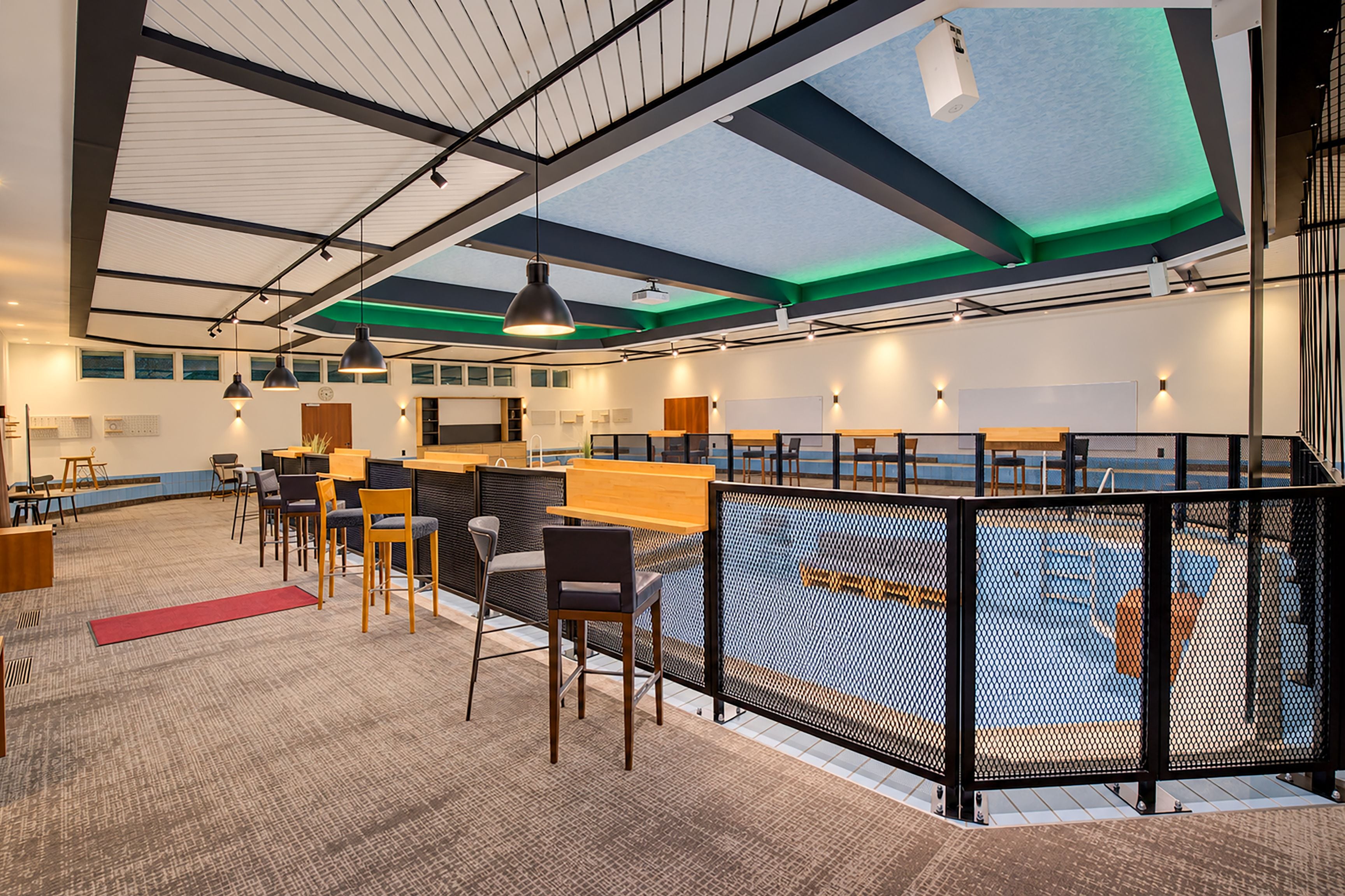 Un espace intérieur doté d’un plafond haut, d’un éclairage moderne et d’un coin salon avec des chaises et des tables.