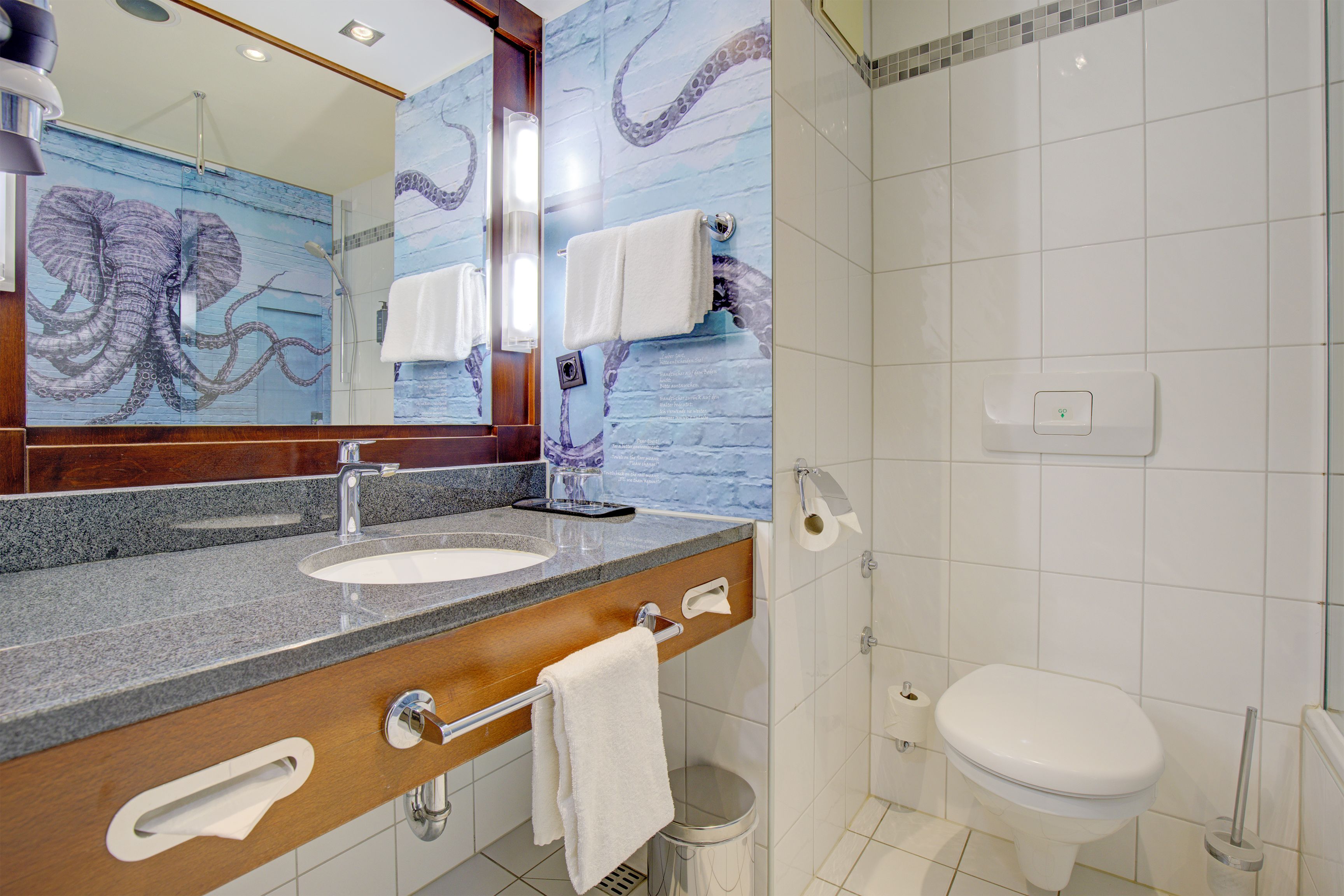 A bathroom with a sink, mirror, towel rack, toilet, and shower.