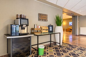 A hotel lobby with a coffee station, a waste bin, a potted plant, and a reception desk. - Seminaris Sunday Hotel Nürnberg (Nuremberg)