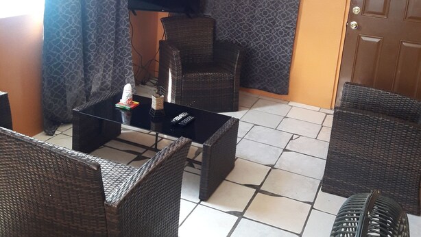 Una habitación con muebles de mimbre, suelo de baldosas y una puerta con ventanal.