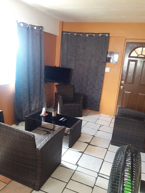 A room with wicker furniture, a tiled floor, and a door with a window.