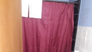 Un baño con inodoro, zona de ducha y suelo de baldosas.