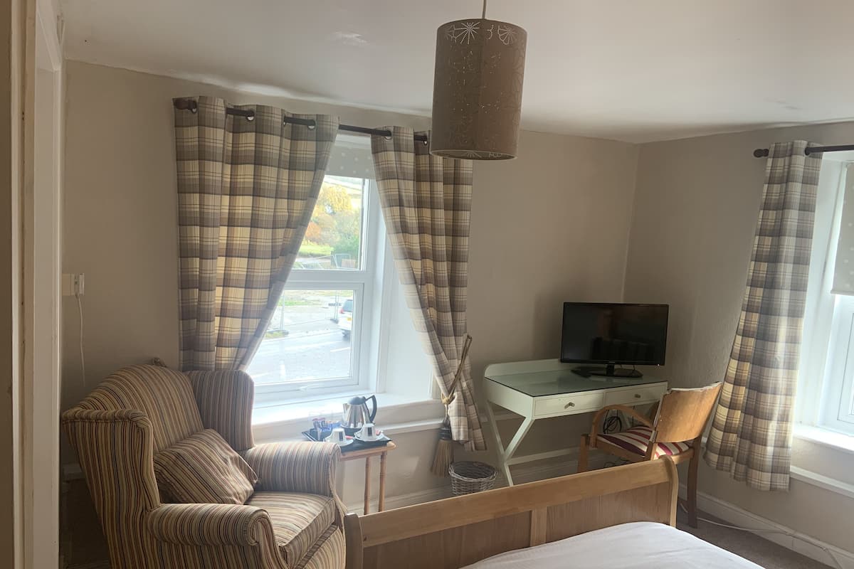 A bedroom with a bed, a TV, a desk, and a chair.