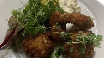 Een bord eten met gefrituurde stukjes, groen en een romige saus.