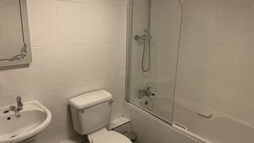 A bathroom with a toilet, sink, and glass-enclosed shower.