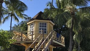 A beach house with a wooden staircase leading to a deck, surrounded by palm trees and beach chairs. - Giggles - Beautiful Bajan Villa with Private Pool (Sunset Crest)
