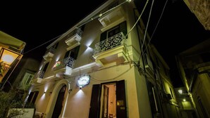 A building with multiple balconies, a lit entrance, and a visible door.