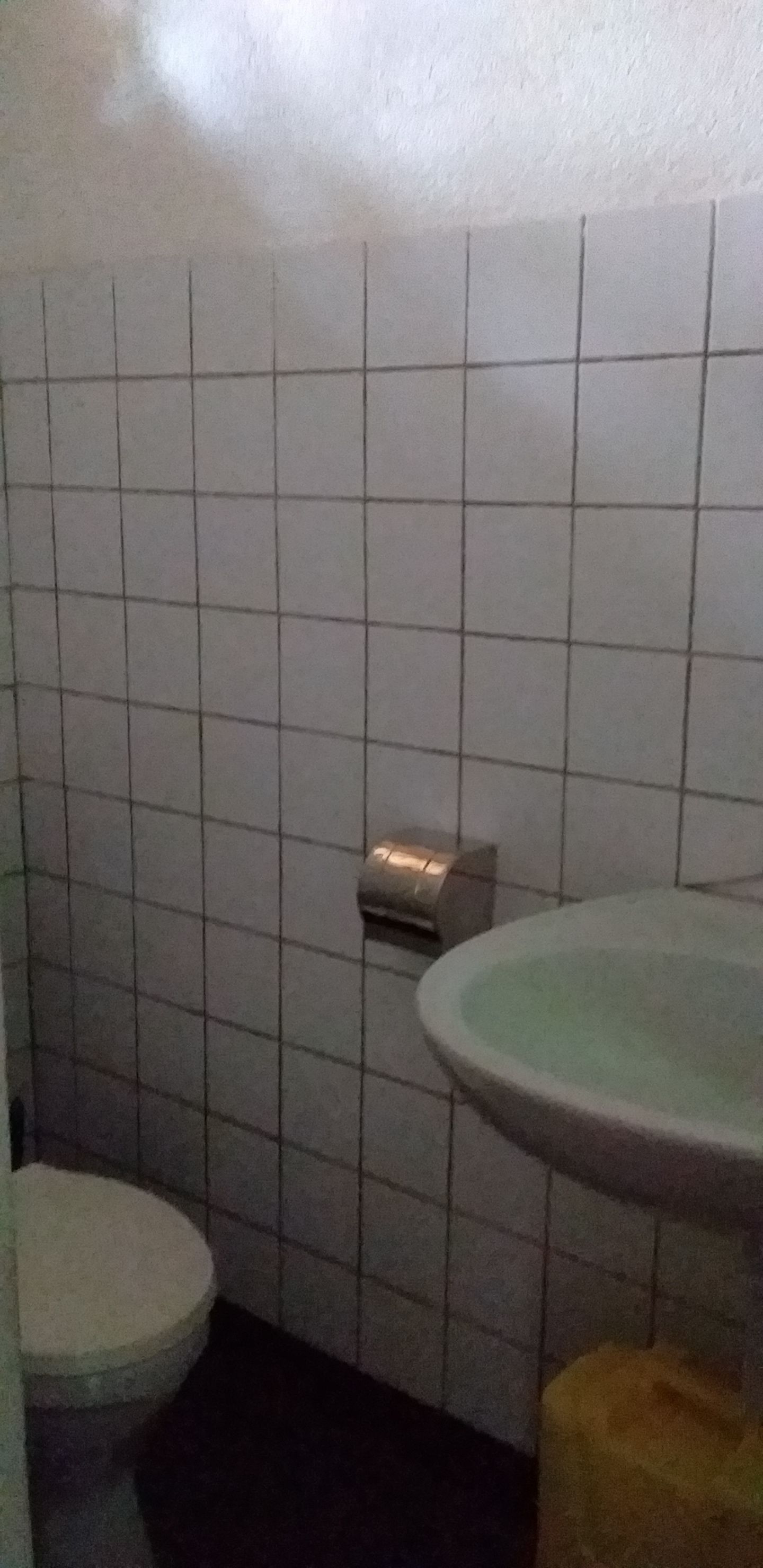 Un baño con inodoro, lavamanos y dispensador de toallas.