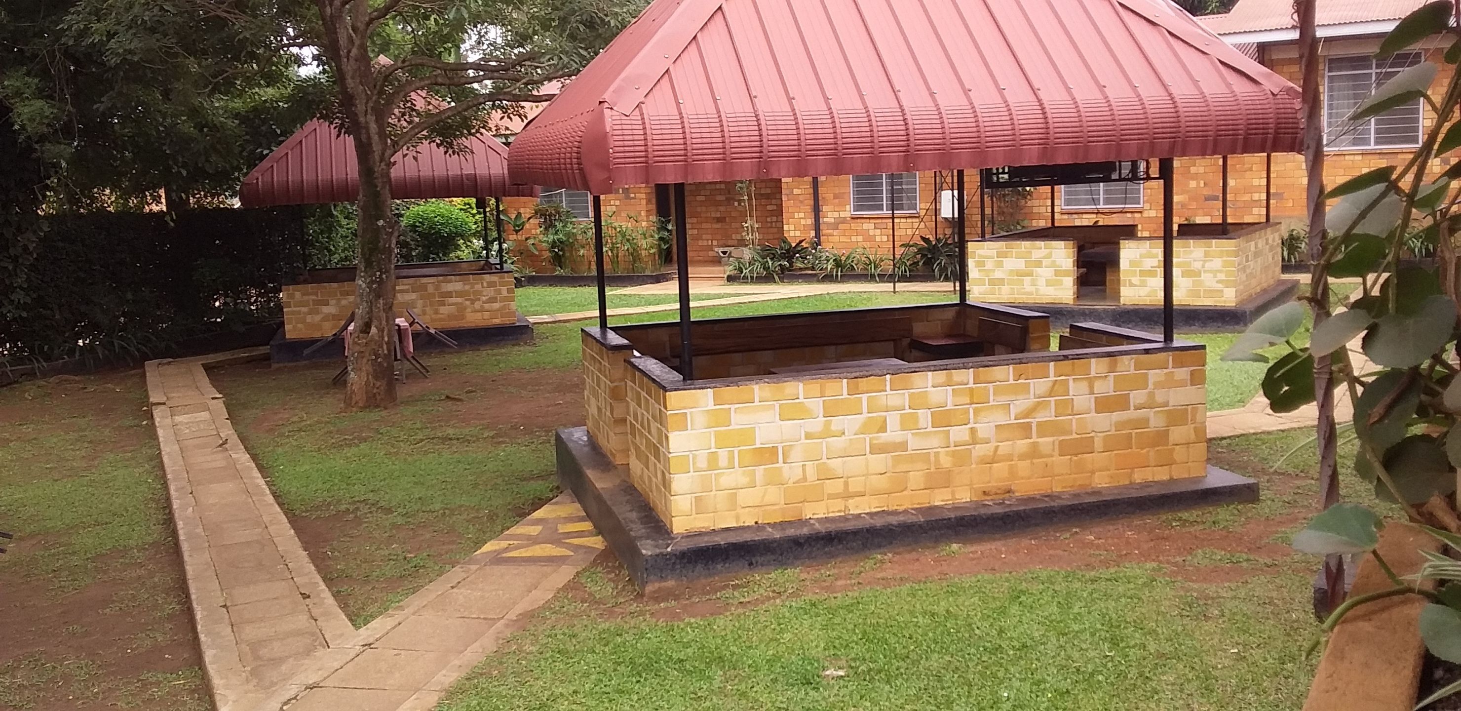 A courtyard with a brick barbecue area and a covered seating area.