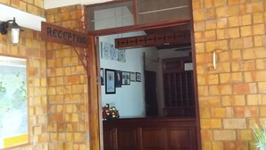 A reception area with a brick wall, a wooden reception desk, and a sign that reads "RECEPTION". - Kolping Hotel Hoima (Hoima)