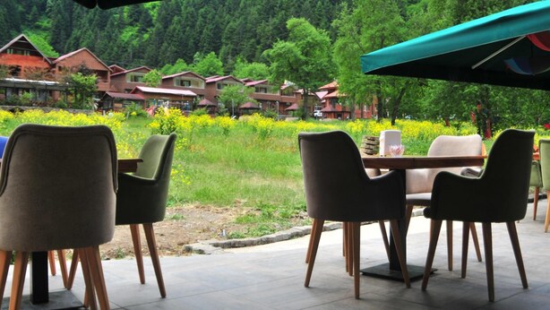 An outdoor seating area with a view of a forested hillside. - Dilek Suit & Cafe (Çaykara)