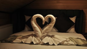 A hotel room with a bed featuring a heart-shaped towel arrangement. - Dilek Suit & Cafe (Çaykara)