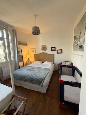 A bedroom with a bed, a bedside table, a lamp, a chair, and a painting on the wall.