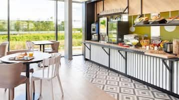A modern outdoor café with a terrace, tables, chairs, and a counter with food and drinks.