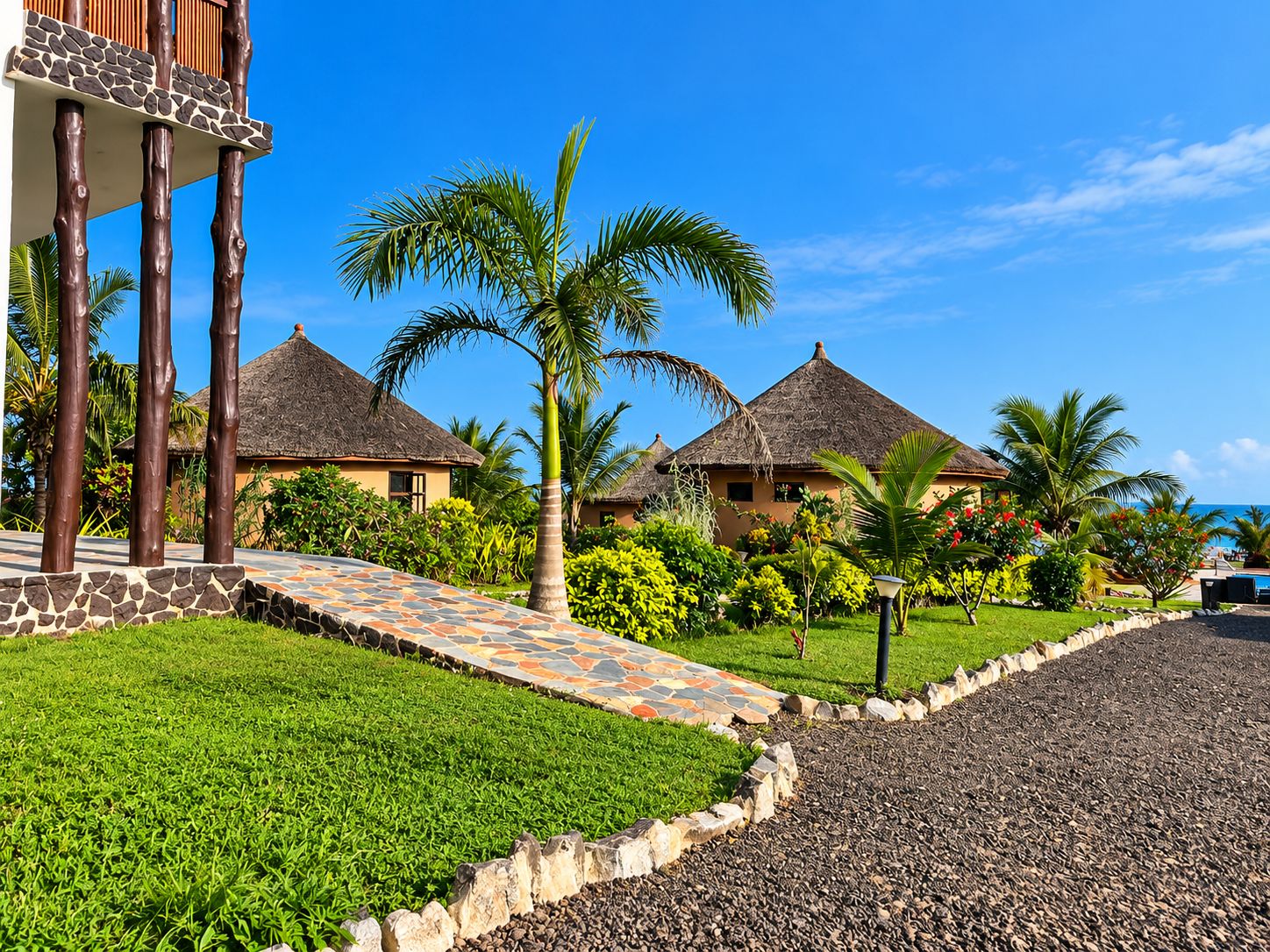 A resort with thatched-roof cottages, a paved walkway, and lush greenery.