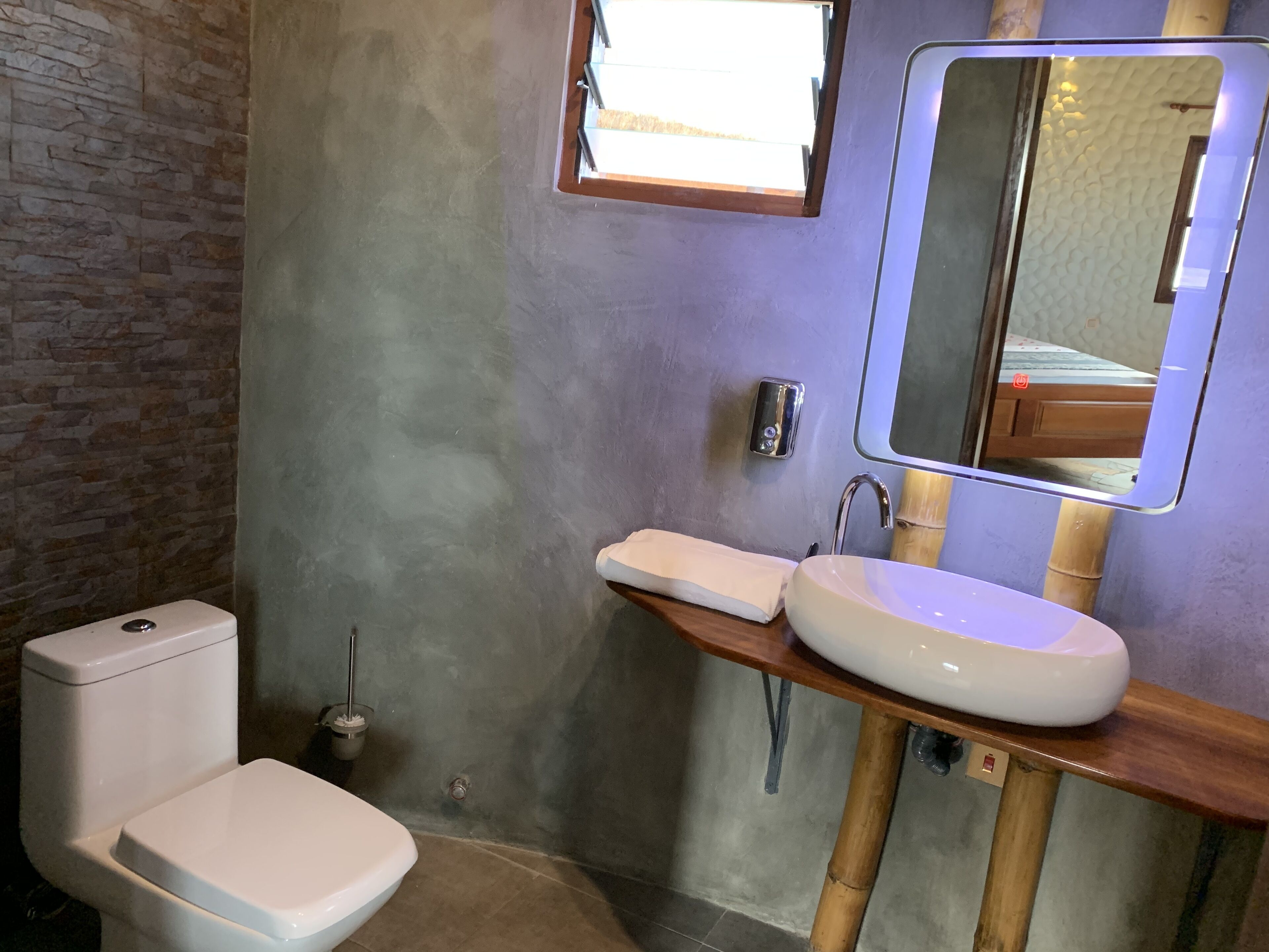 A bathroom with a toilet, sink, and mirror.